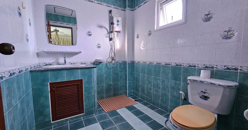 Ensuite bathroom with walk-in shower, electric water heater, vanity sink, WC, and tiled walls in a Phuket villa.