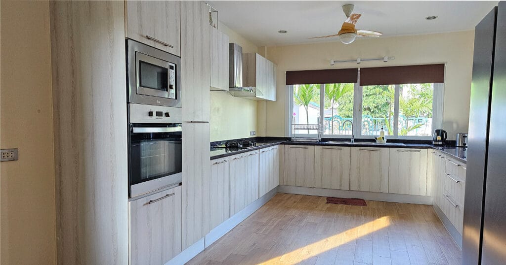 Modern fitted kitchen with marble countertops, electric oven, microwave, gas hob, and natural light from uPVC windows.