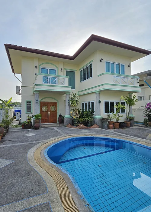 Front view of a two-storey 3-bedroom villa in Phuket with a private swimming pool, balconies, and tropical plants.